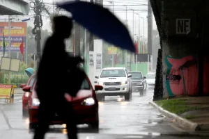 Pedestre caminha sob chuva em Aracaju