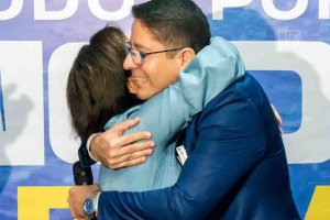 Foto da pré-candidata a prefeita de Aracaju, Emília Corrêa, durante anúncio do pré-candidato a vice prefeito, Ricardo Marques.Emília está usando um vestido longo jeans, cinto rosa e sapato bico fino rosa.